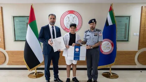 El menor homenajeado entre representantes de la Policía de Abu Dhabi. (X)