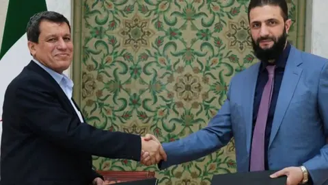 El presidente interino de Siria, Ahmed al Sharaa, y el comandante de las fuerzas kurdas sirias, Mazloum Abdi, se dan la mano después de que Siria alcanzara un acuerdo para integrar a las Fuerzas de Siria Democrática (FSD), lideradas por kurdos, en las instituciones estatales. (X)
