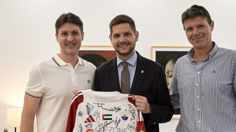 El alcalde de Gandía, en el centro de la imagen, recibe la camiseta del Sharjah. (X)