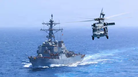 El USS Donald Cook transita por el mar Ar&aacute;bigo mientras un MH-60S Sea Hawk vuela cerca. (Centcom)