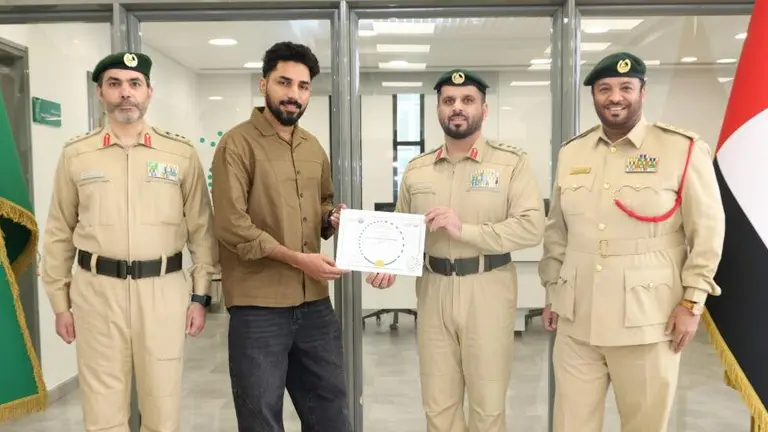 El expatriado junto a miembros de la polic&iacute;a tras devolver el dinero. (Dubai Police)