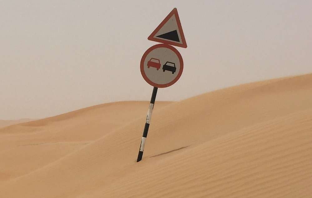 Señal de tráfico enterrada en arena en la carretera de Liwa a Tal Moreb. (EL CORREO)