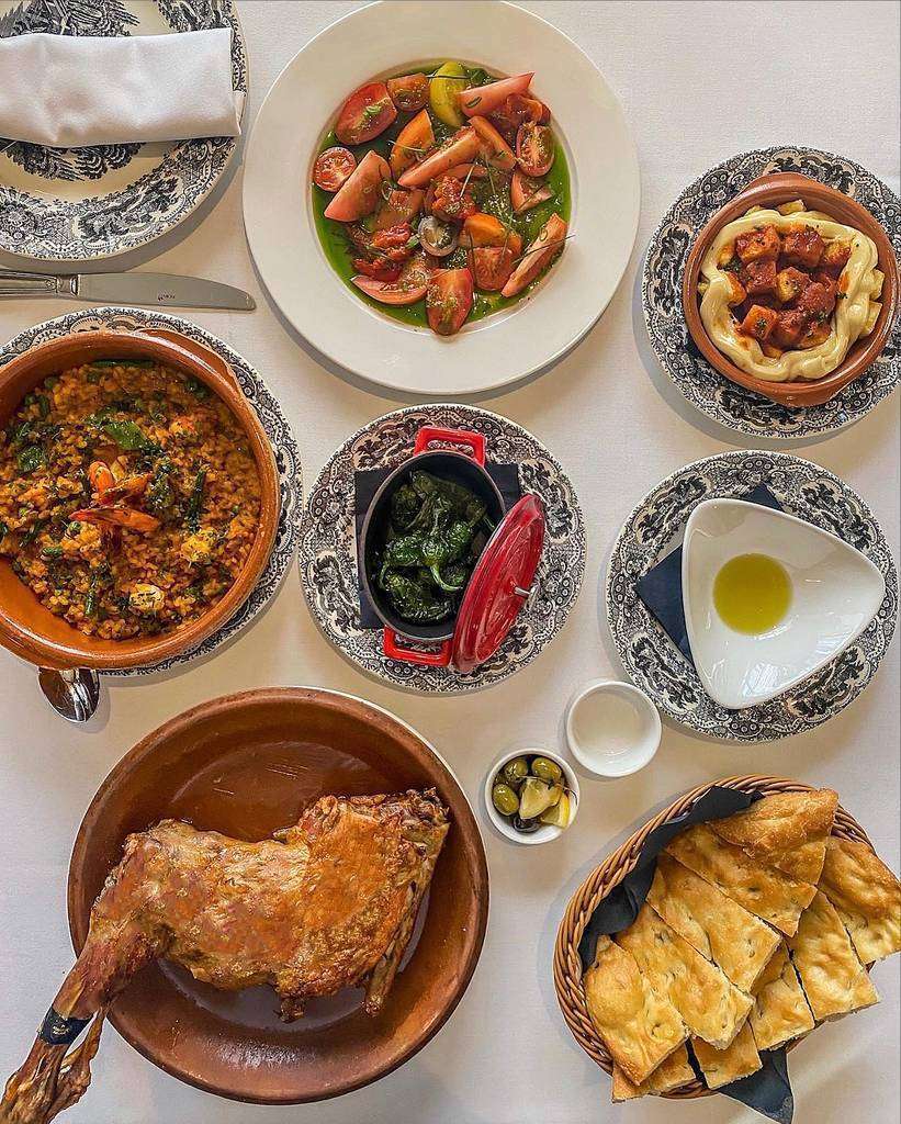Distintos platos en Asador de Aranda en Dubai, entre los cuales no falta la torta de Aranda ni el arroz caldoso. (Cedida)
