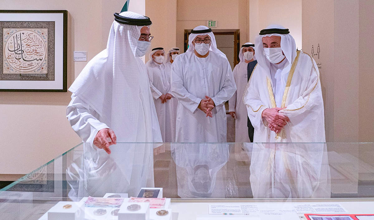 El ministro de Salud y Prevención de Emiratos Árabes, Abdul Rahman bin Mohammed Al Owais -en el centro-, acompaña a su Alteza el jeque Sultán bin Mohammed Al Qasimi, gobernante de Al Sharjah, en su visita la exposición de arte 'Letras Luminosas'. (WAM)
