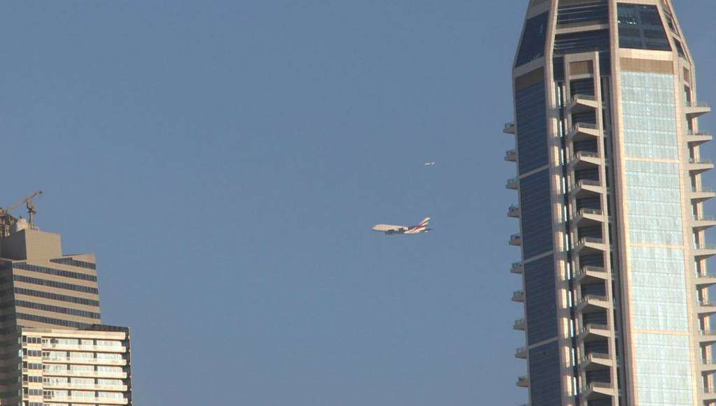 El avión A380 de Emirates Airline entre rascacielos de Dubai Marina.