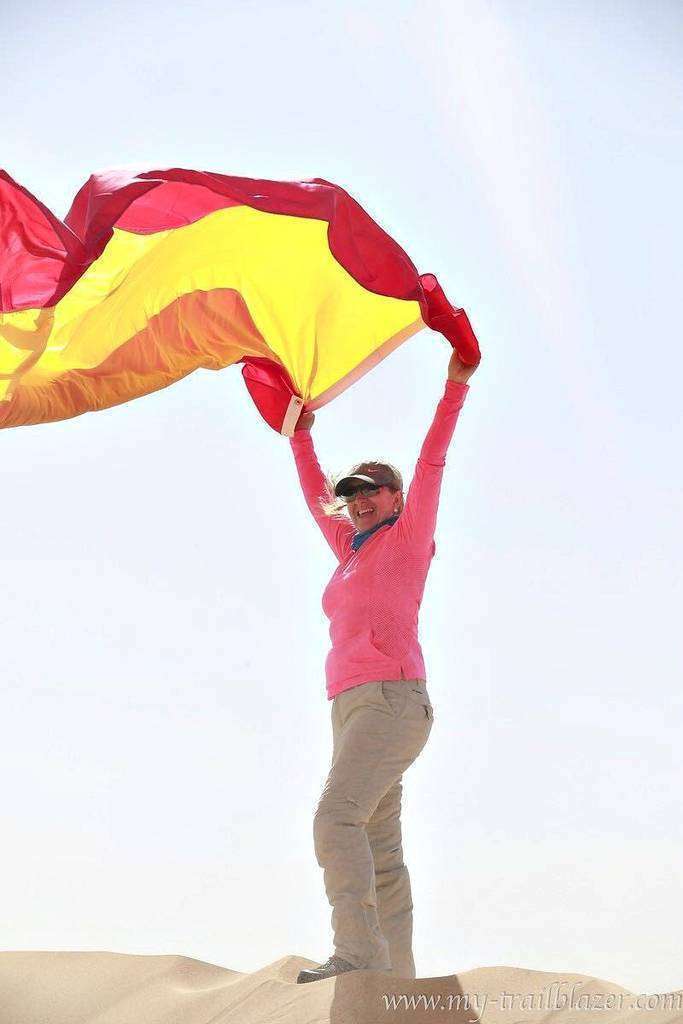 María Ángeles Alom, sobre una duna bandera de España en mano. (Cedida)