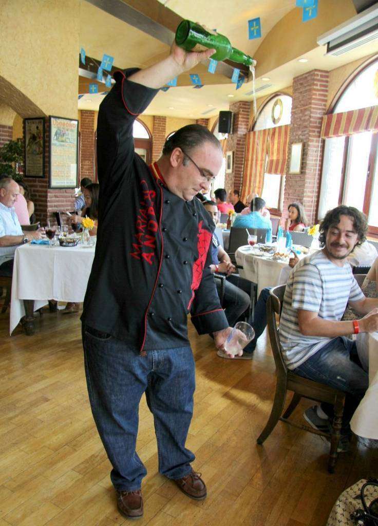 Mariano Andrés escancia un culín de sidra en el Seville's. (EL CORREO)