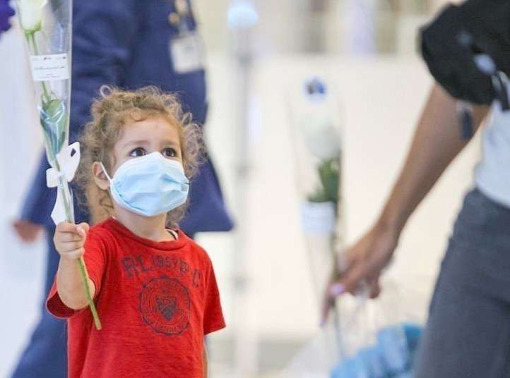 Niña libanesa muestra la rosa blanca recibida a su llegada al Aeropuerto de Dubai. (WAM)