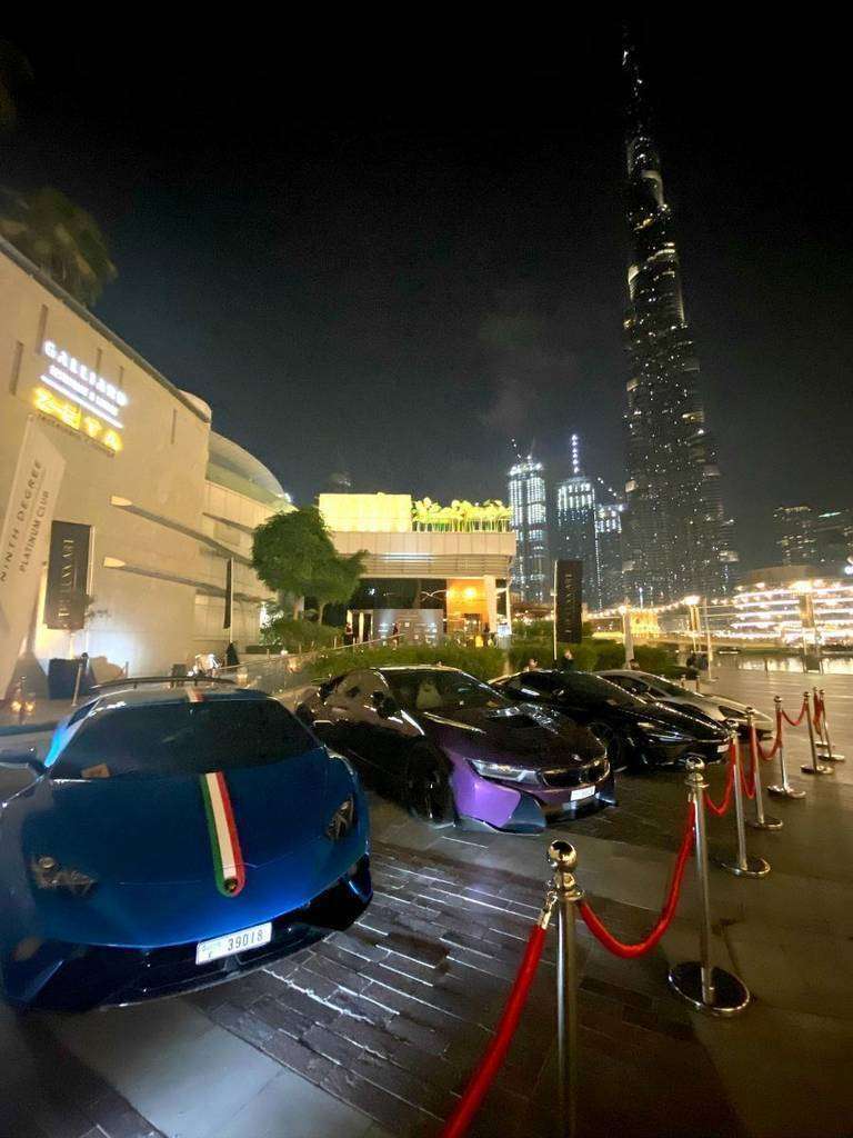 Súper coches de lujo estacionados en la puerta de 99 Sushi Bar Dubai con el Burj Khalifa de telón en la noche de la inauguración oficial del restaurante. (Cedida)