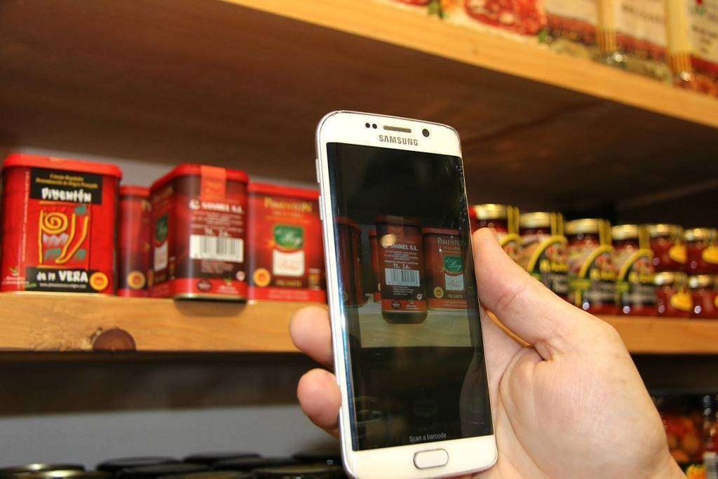 Un cliente realiza una búsqueda con su móvil a través del código de barras en la tienda de La Despensa. (EL CORREO)